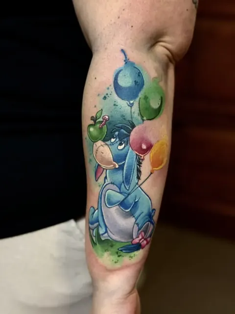 Bourriquet avec des ballons colorés, tatouage en couleur sur l’avant-bras
