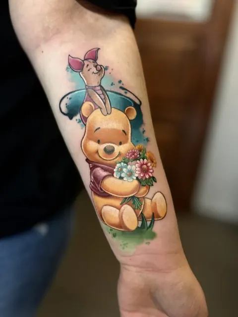 Winnie l’Ourson avec Porcinet et un bouquet de fleurs, tatouage en couleur sur l’avant-bras
