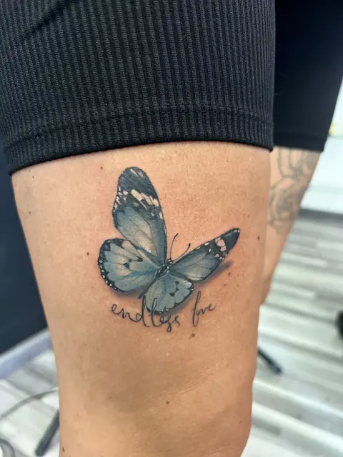 Blauer Schmetterling mit Schriftzug «endless love» am Oberschenkel, farbig