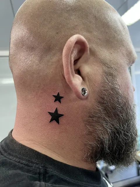 Zwei schwarze Sterne hinter dem Ohr am Hals, minimalistisch